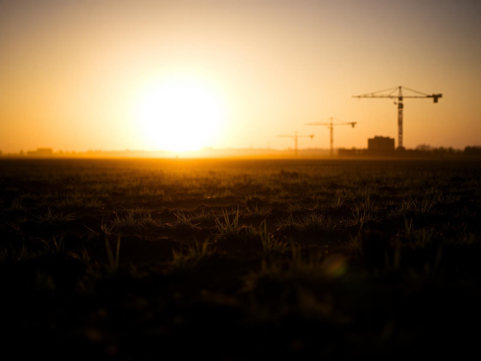 Open land at sunrise with distant construction